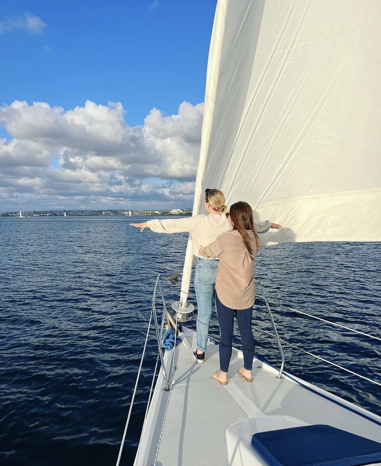 A guest with arms outstretched on the bow under sail