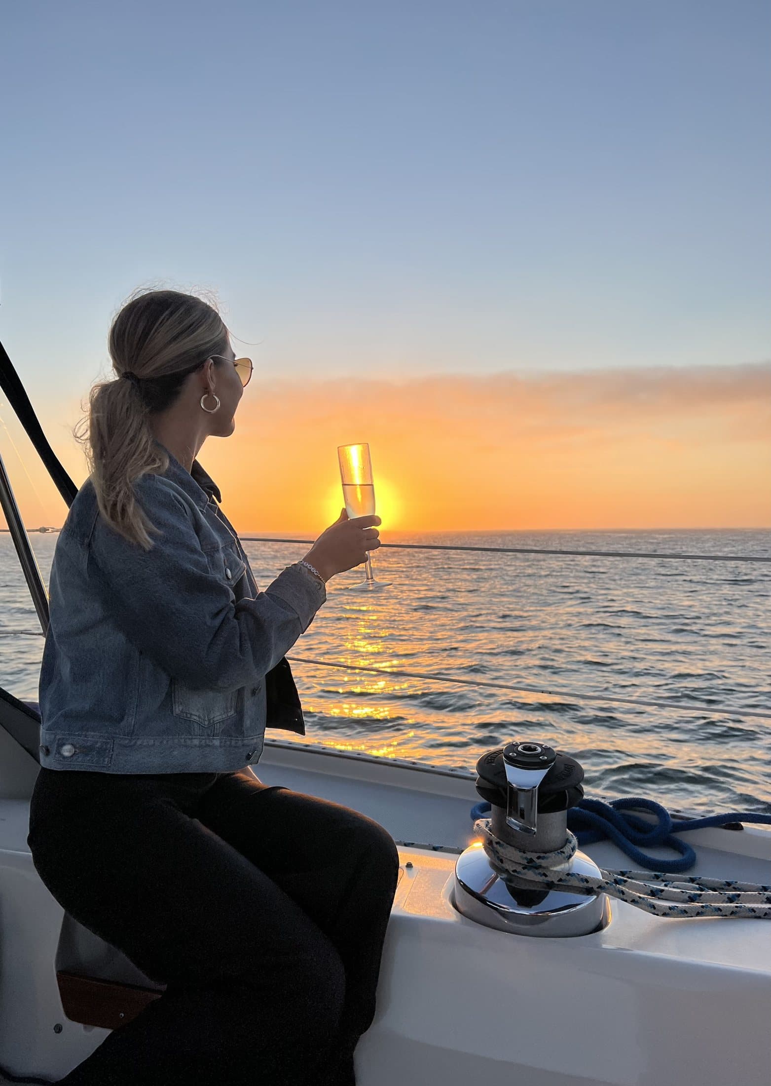 A guest raising a glass of champagne toward the setting sun on San Diego Bay